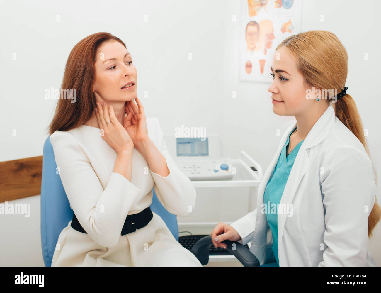 Il medico ascolta le lamentele del paziente mentre il paziente punta verso la gola, Foto Stock