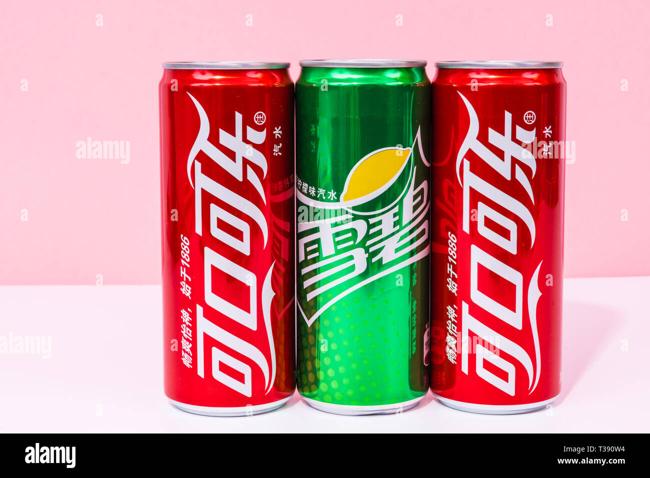 Peniscola , Castellon, Spagna - 07 aprile 2019 : scritto in cinese due lattine di coca cola e una possibile sprite , bevande isolato su un colore rosa backgroun Foto Stock