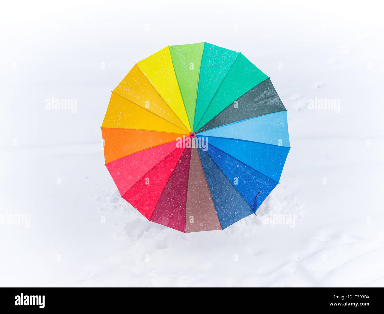 Ombrello arcobaleno sul bianco della neve. Inverno immagine a tema Foto Stock