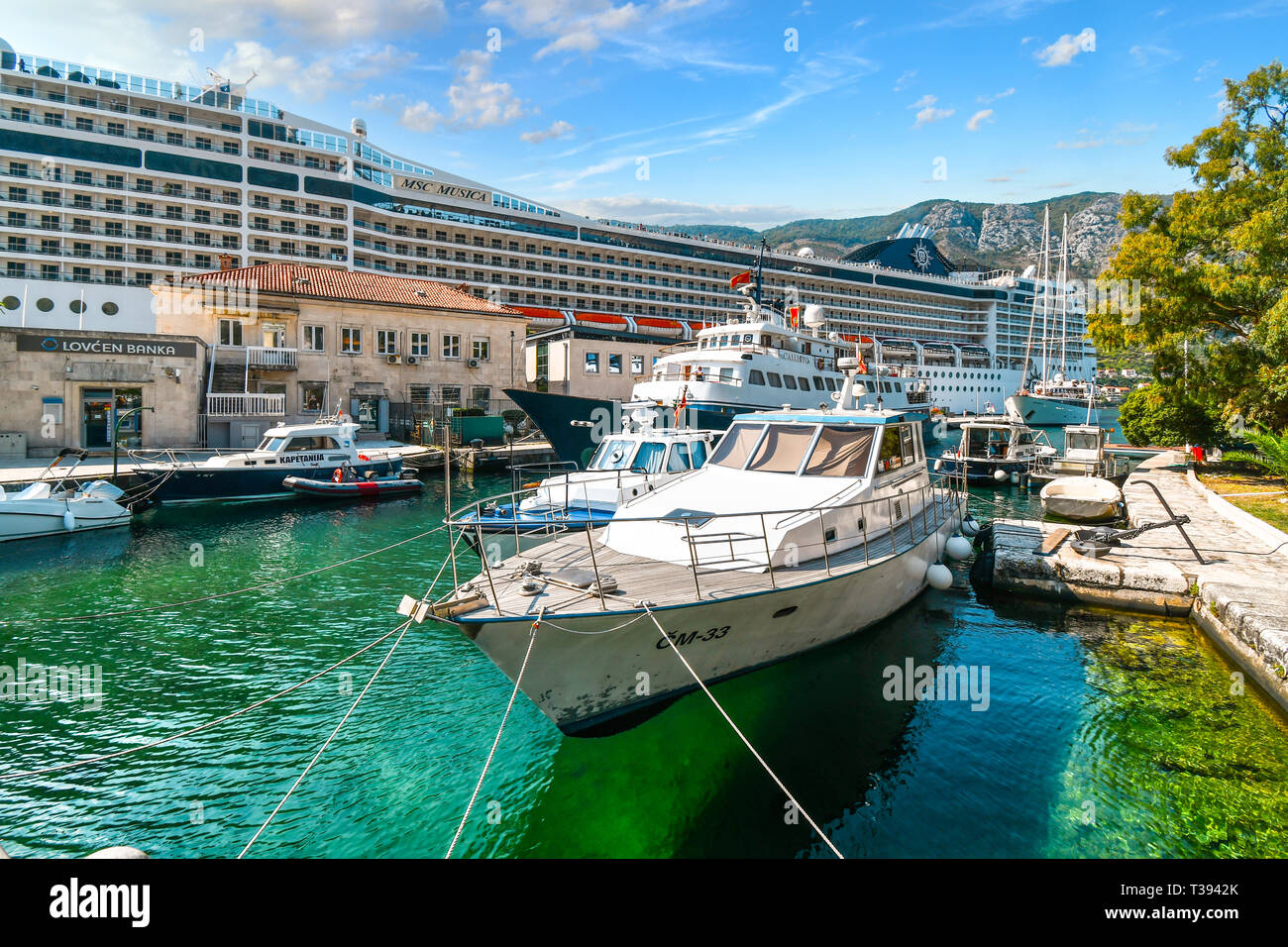 Un pomeriggio occupato presso la struttura Boka, porto di Kotor Montenegro come varie barche e yacht, zattere ed una grande nave da crociera condividono lo spazio nella città del mediterraneo Foto Stock