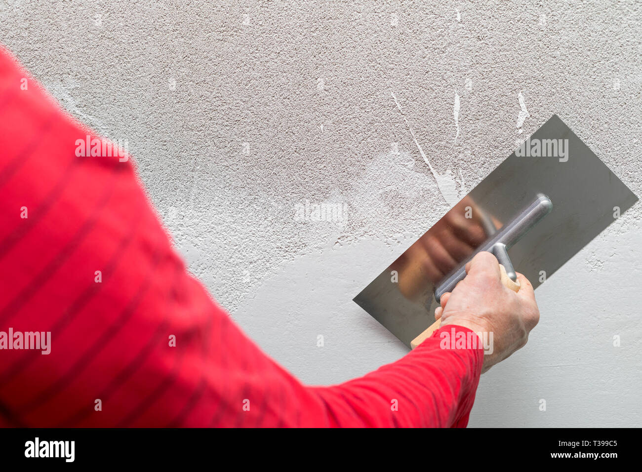 Vicino la foto di un uomo con una spatola - Riempimento nelle pareti di cemento in un nuovo appartamento Foto Stock