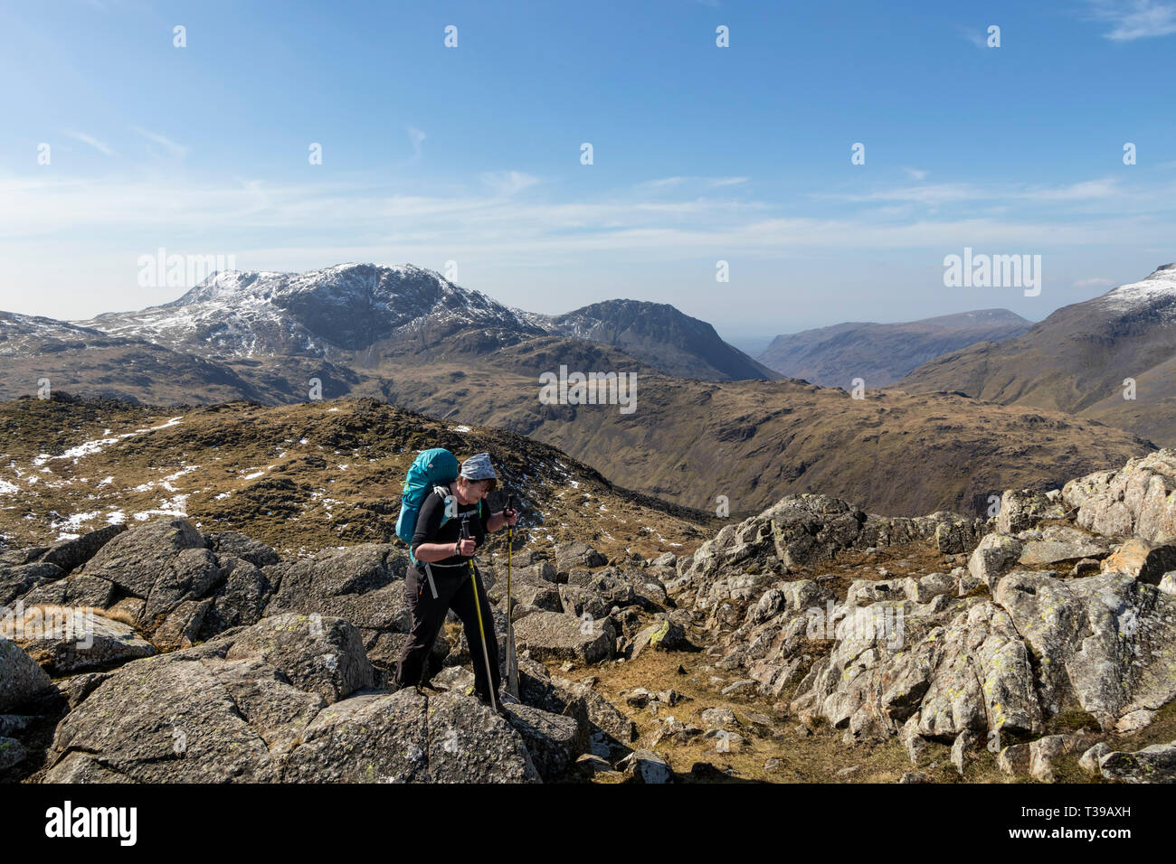 Walker avvicinarsi al vertice Area di Glaramara con le montagne del Grande Fine e Lingmell come sfondo, Lake District, Cumbria, Regno Unito Foto Stock