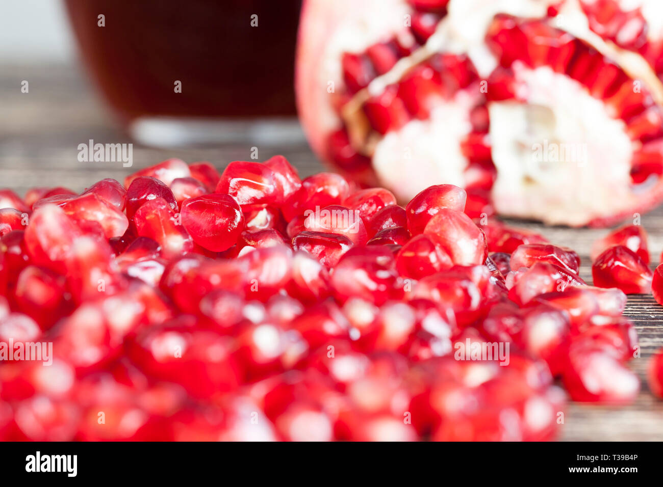 Rosso Verde pelati melograno su legno tabella stilizzata è verniciata di nero accanto ad esso è con un bicchiere di succo di melograno, molto cibo sano Foto Stock