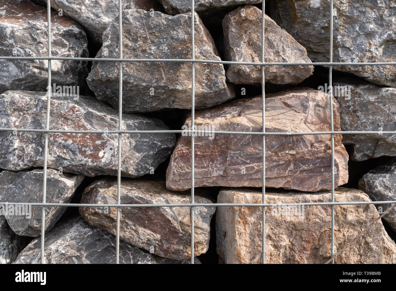 Una chiusura di una pila di rocce di granito in una gabbia di metallo utilizzato per la prevenzione delle inondazioni. Foto Stock