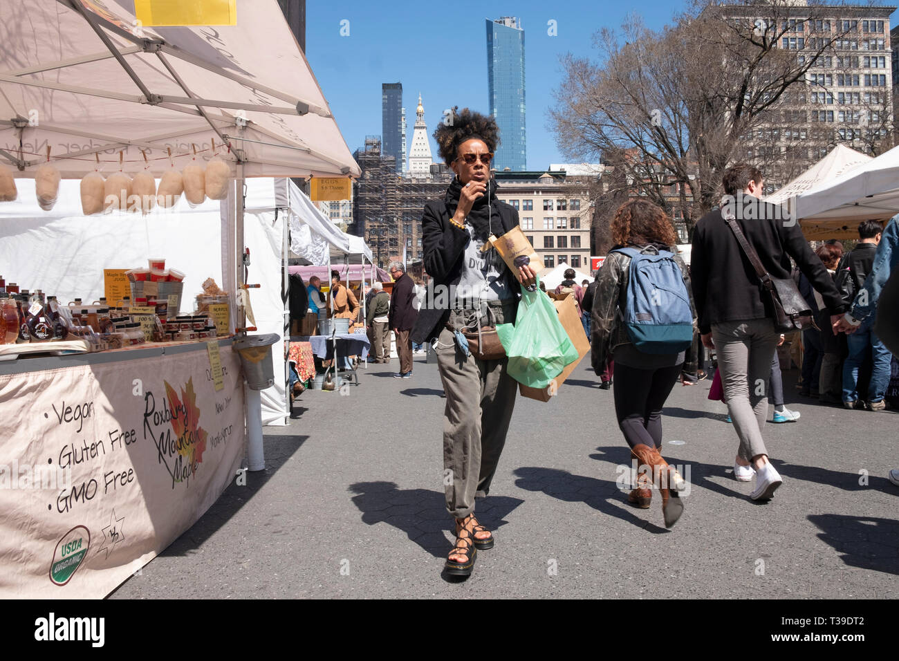 Una donna attraente mangiare patatine e camminare attraverso l unione Piazza Mercato verde a Manhattan, New York City. Foto Stock