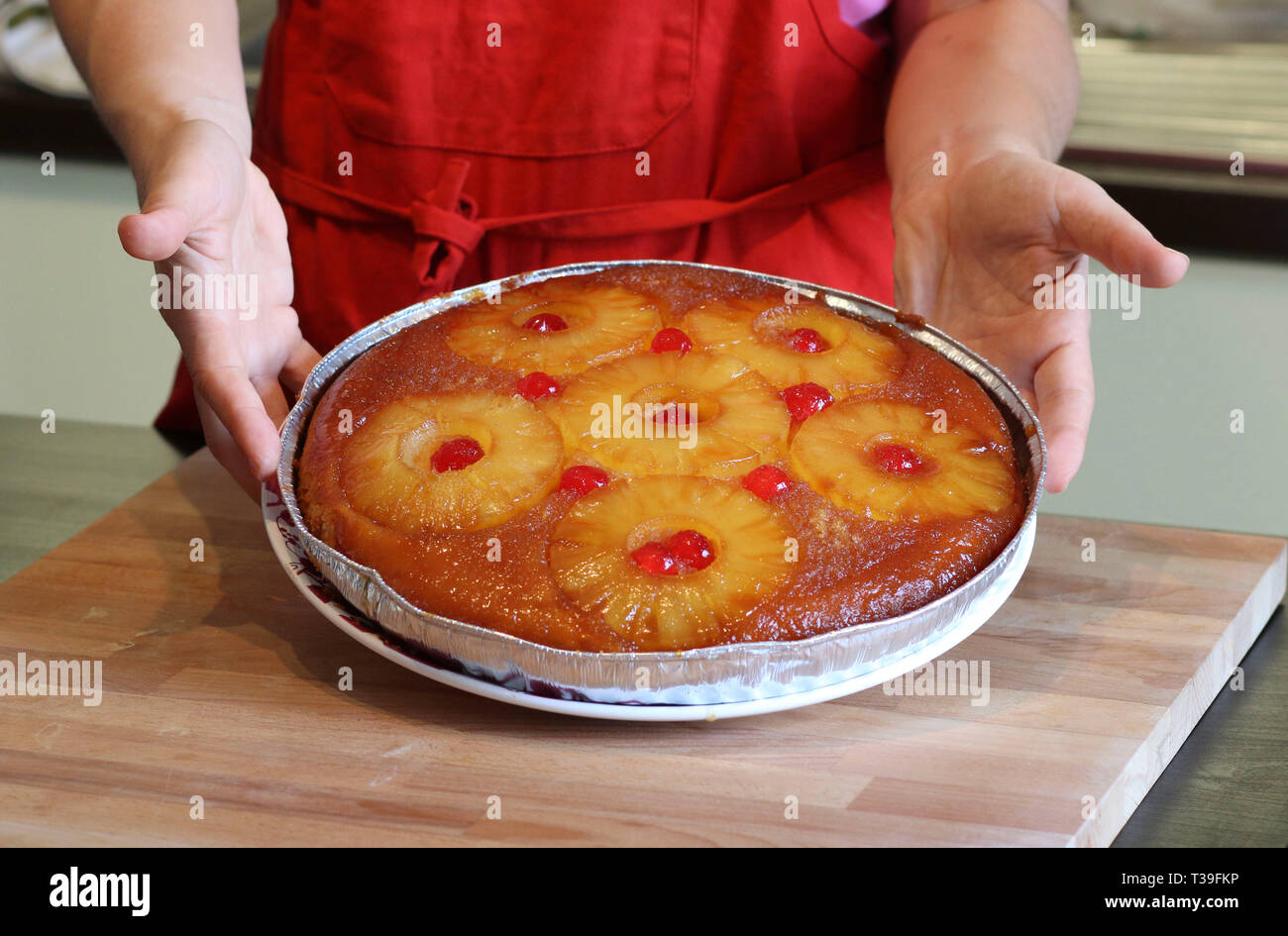 Donna mani con torta capovolta. Crostate di ananas tradizionali fatte in casa. Direttamente sopra. Foto Stock