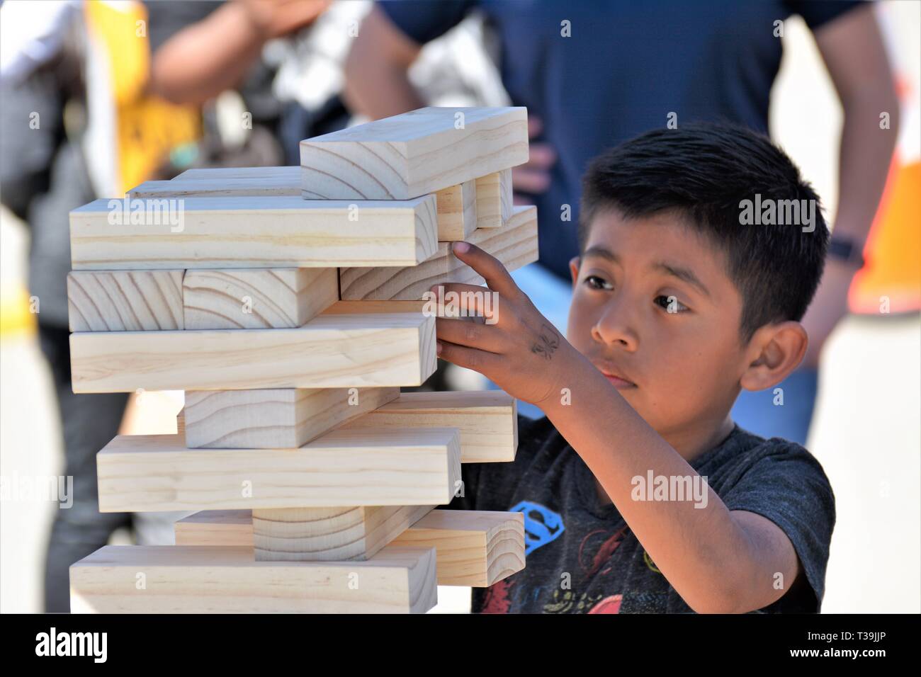 Ragazzo giovane imparando circa accatastamento ed equilibrio e così con blocchi da costruzione in legno Foto Stock