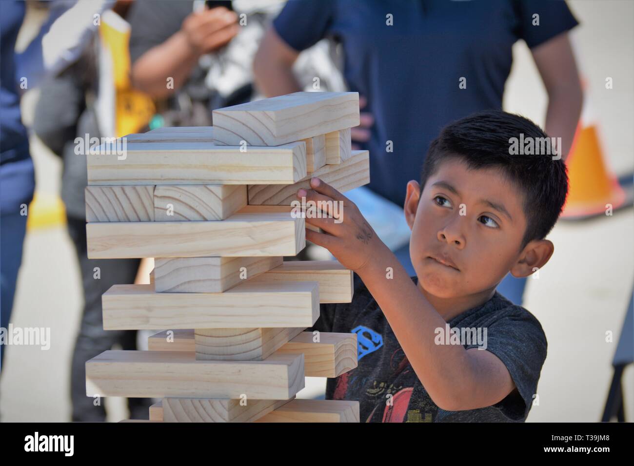 Ragazzo giovane imparando circa accatastamento ed equilibrio e così con blocchi da costruzione in legno Foto Stock
