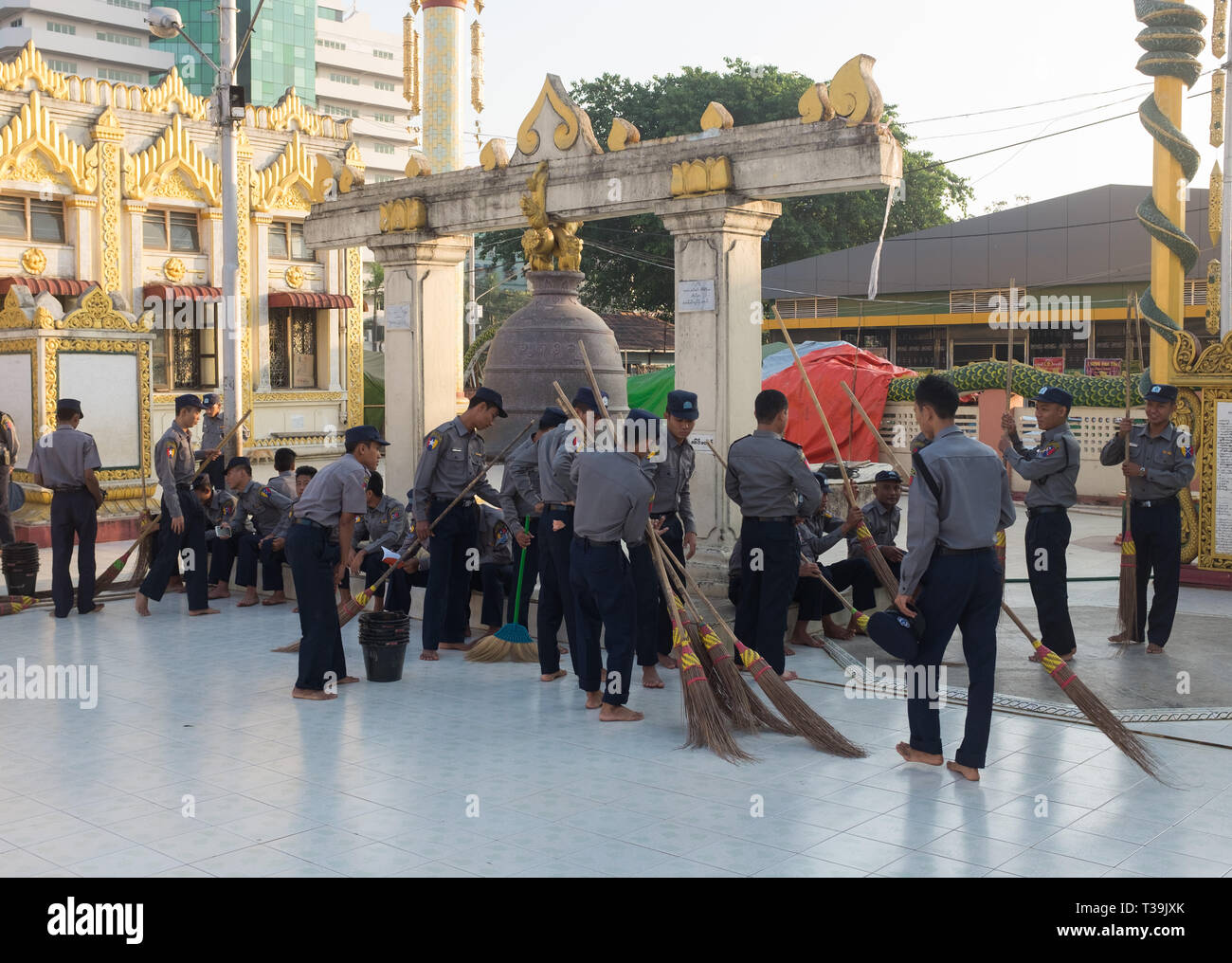 Gruppo di poliziotti volontario per pulire il terreno della Pagoda Botataung, Yangon, Myanmar (Birmania). Foto Stock
