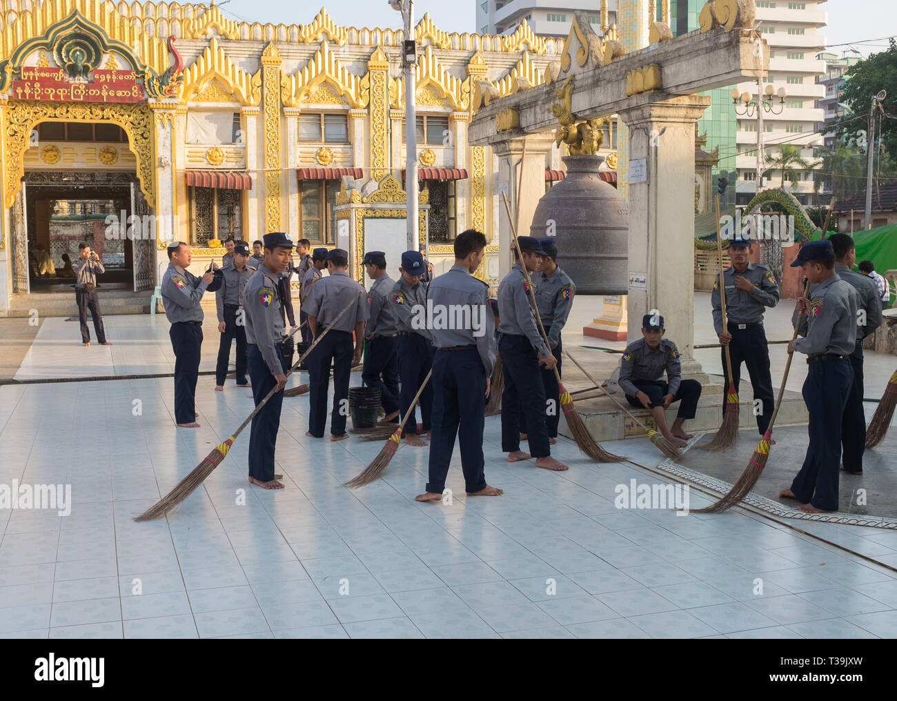 Gruppo di poliziotti volontario per pulire il terreno della Pagoda Botataung, Yangon, Myanmar (Birmania). Foto Stock