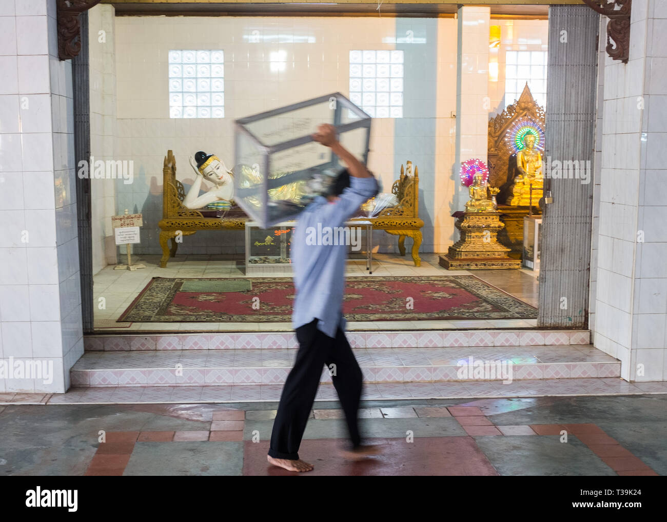 L'uomo posizionando la donazione scatole la mattina presto all'interno del Chauk Htat Gyi Pagoda Tempio del 65 metro lungo Buddha reclinato immagine, Yangon,Myanma Foto Stock