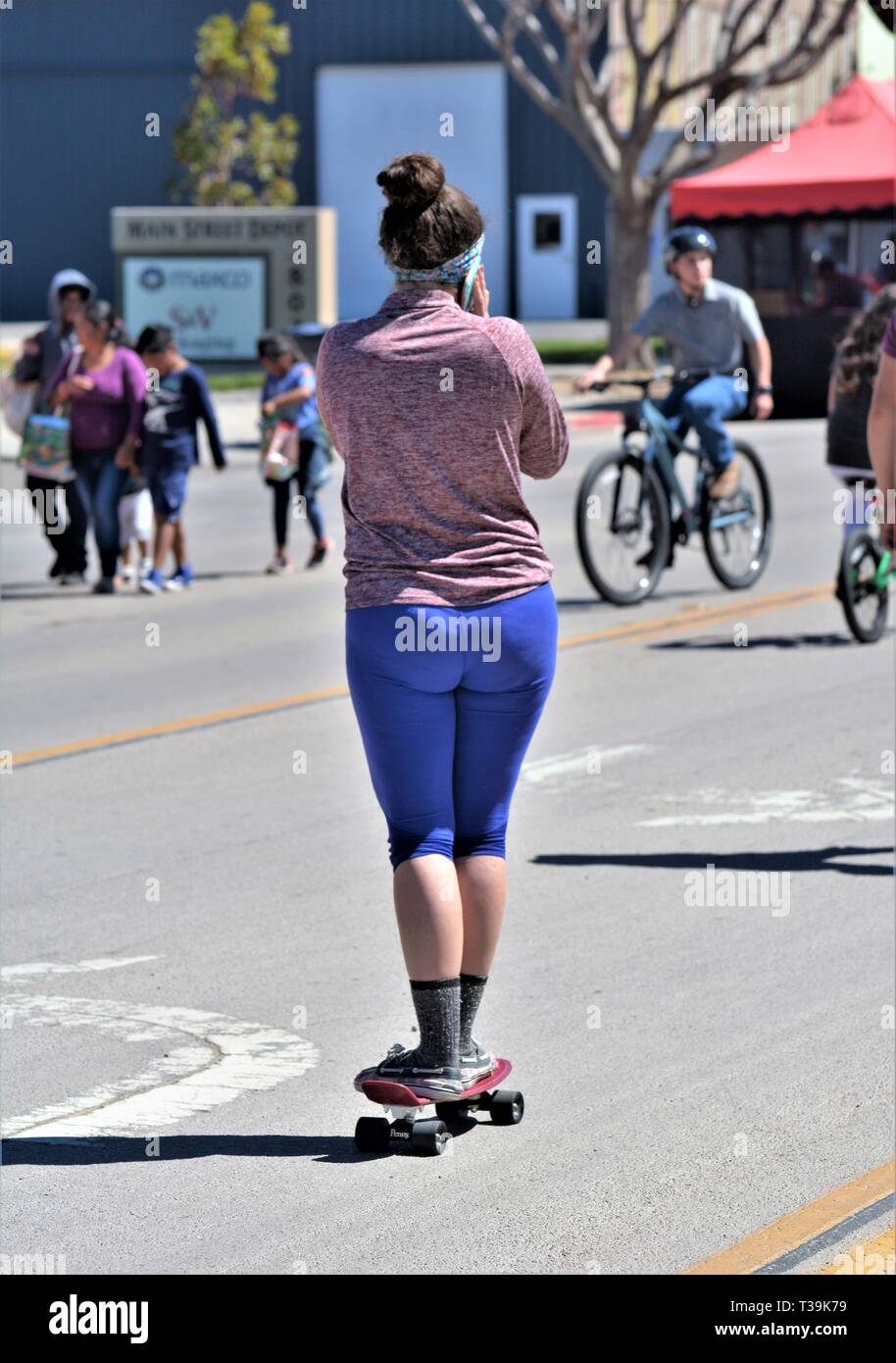 donna di età teenager sullo skateboard in strada durante l'evento pubblico, piuttosto che camminare a lunga distanza Foto Stock