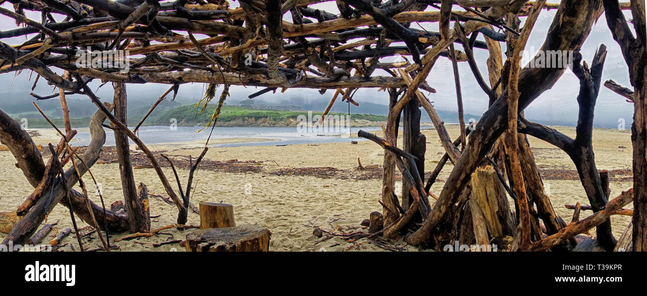 Guardando fuori da un ripiego beach hut fuori di un corpo di acqua di alimentazione nell'oceano. Foto Stock