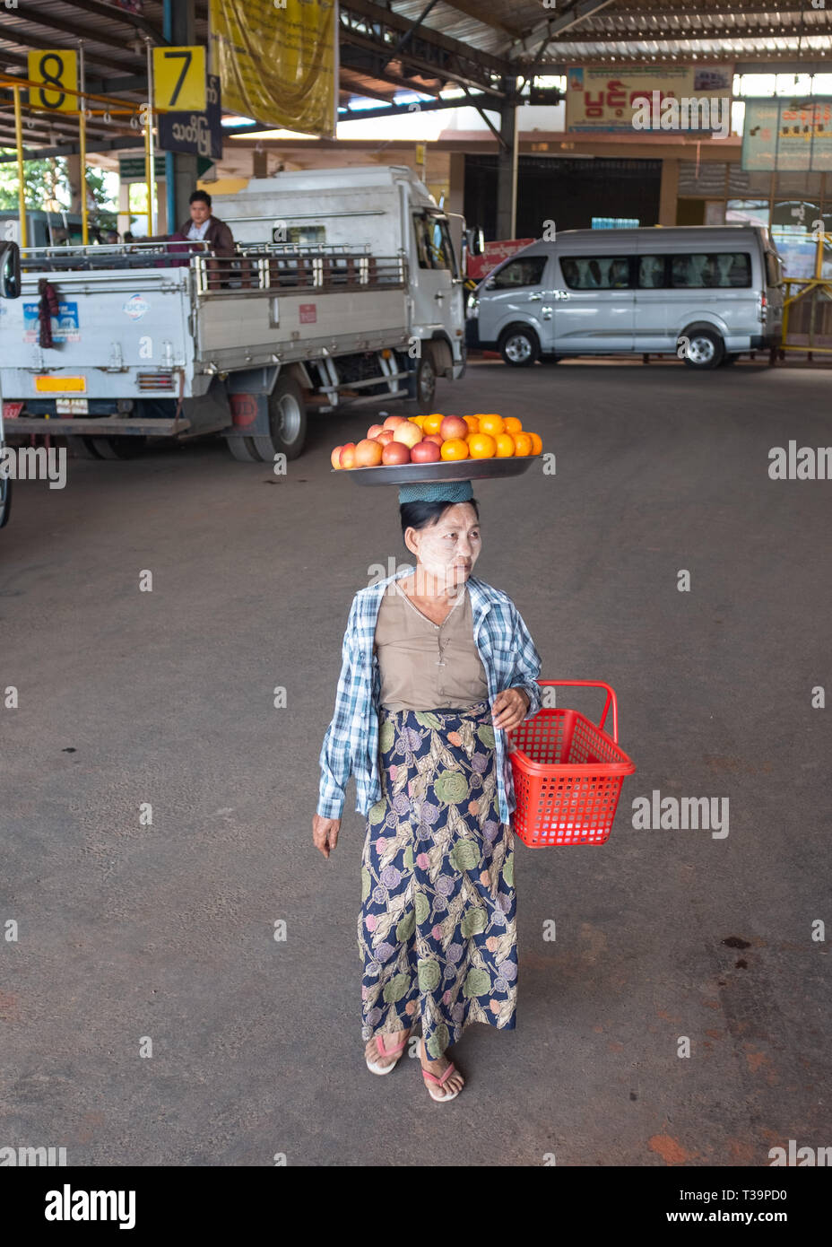 Donna birmano con thanaka face painting che porta una piastra con la frutta in testa alla stazione degli autobus di Kinpun Vlllage,Kyaiktiyo,Myanmar. Foto Stock