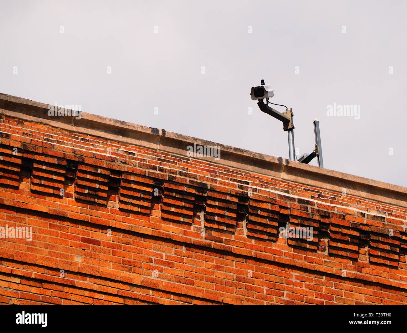 Sorveglianza / videocamera di sicurezza sulla parte superiore di un edificio in mattoni Foto Stock