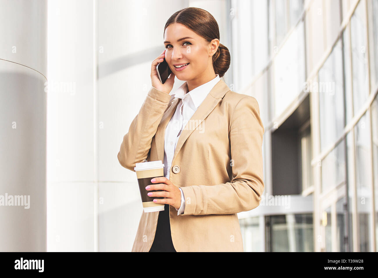 Lei è sempre in contatto. Ritratto di giovane e attraente donna in smart  abbigliamento casual parlando su il suo smart phone e sorridere mentre un  caffè bra Foto stock - Alamy