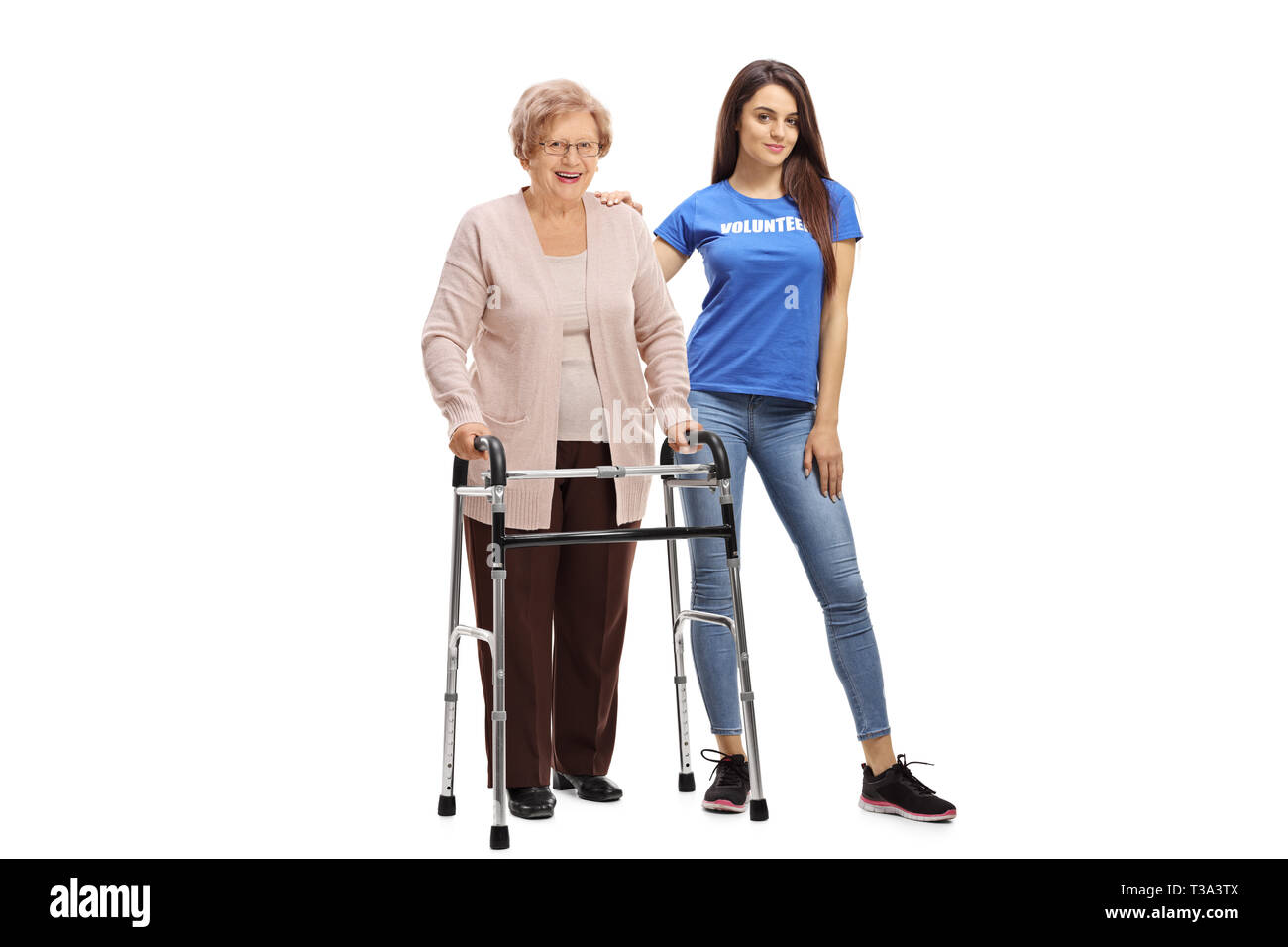 A piena lunghezza Ritratto di una donna senior con un walker in piedi con una giovane donna volontario isolato su sfondo bianco Foto Stock