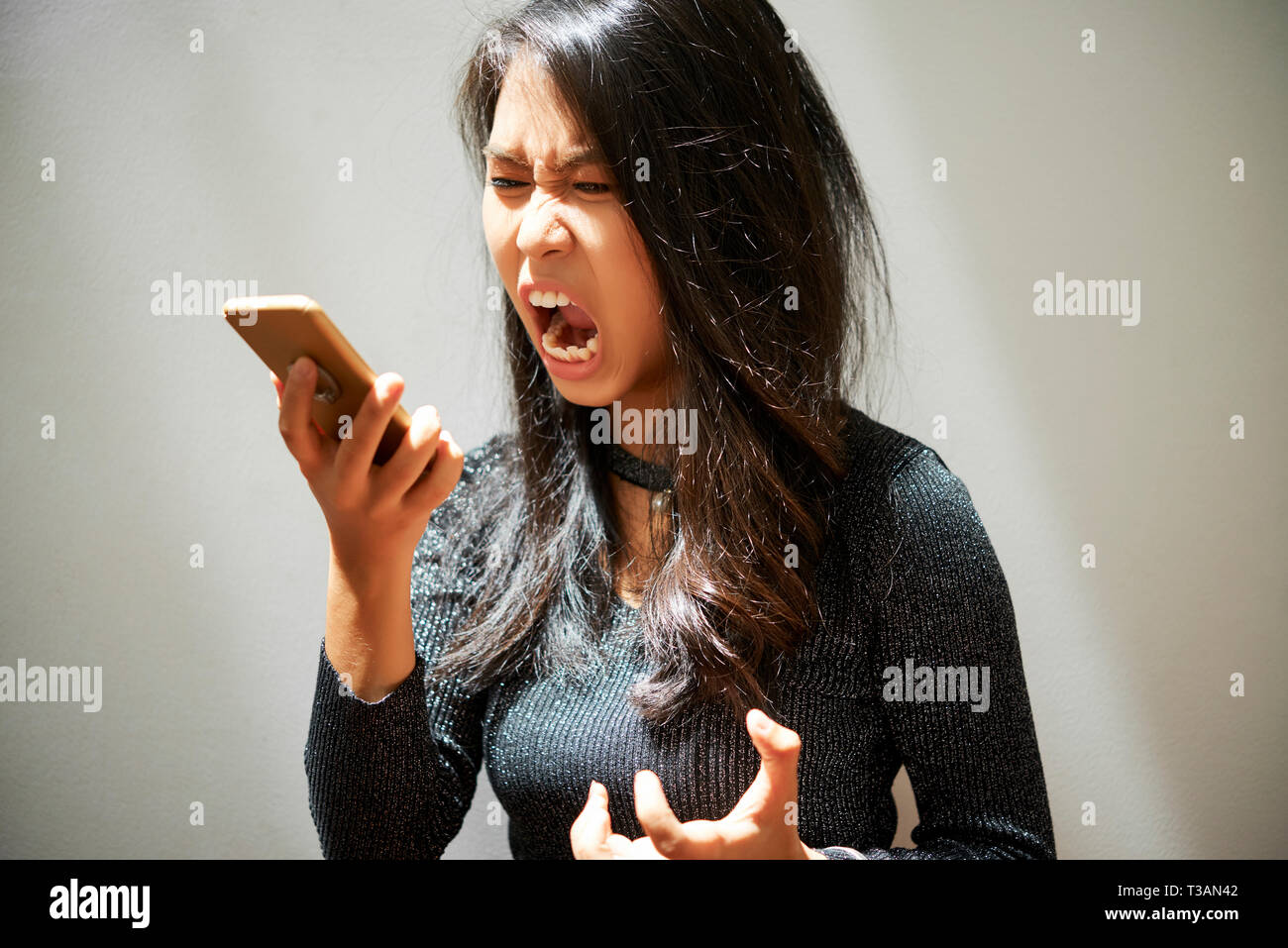 La donna grida di smartphone Foto Stock