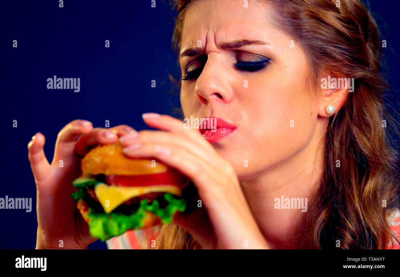 Donna malata mangiare hamburger junk food Foto Stock