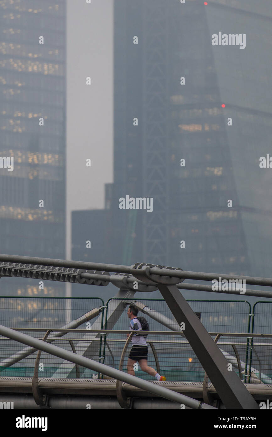 Londra, Regno Unito. 8 Apr 2019. Pendolari camminare e correre sul Millennium Bridge - TfL emette un avviso al tubo pendolari che Londra è colpite da elevati livelli di inquinamento oggi come sopra la terra la città è avvolta nella nebbia. Incoraggia gli uomini a camminare,ciclo e correre al lavoro per facilitare la scadente qualità dell'aria. Credito: Guy Bell/Alamy Live News Foto Stock