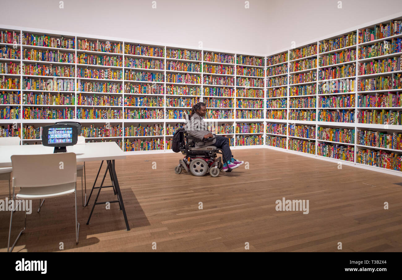 Londra, Regno Unito. 8 Aprile, 2019. L'artista Yinka Shonibare CBE, alla Tate Modern accanto alla sua installazione la British Library, le ultime opere d'arte di essere acquisita da Tate.La British Library è un sito-specifica installazione con una piattaforma digitale per i visitatori a partecipare alla discussione. Una celebrazione della diversità della popolazione britannica contiene 6,328 libri rilegati in "dutch cera stampa', un tessuto caratteristicamente usati dall'artista nel suo lavoro. Credito: Malcolm Park/Alamy Live News. Foto Stock