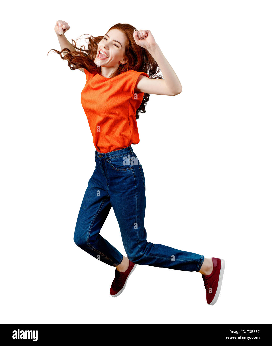 Lunghezza completa di zenzero felice donna in maglietta e jeans jumping. Foto Stock