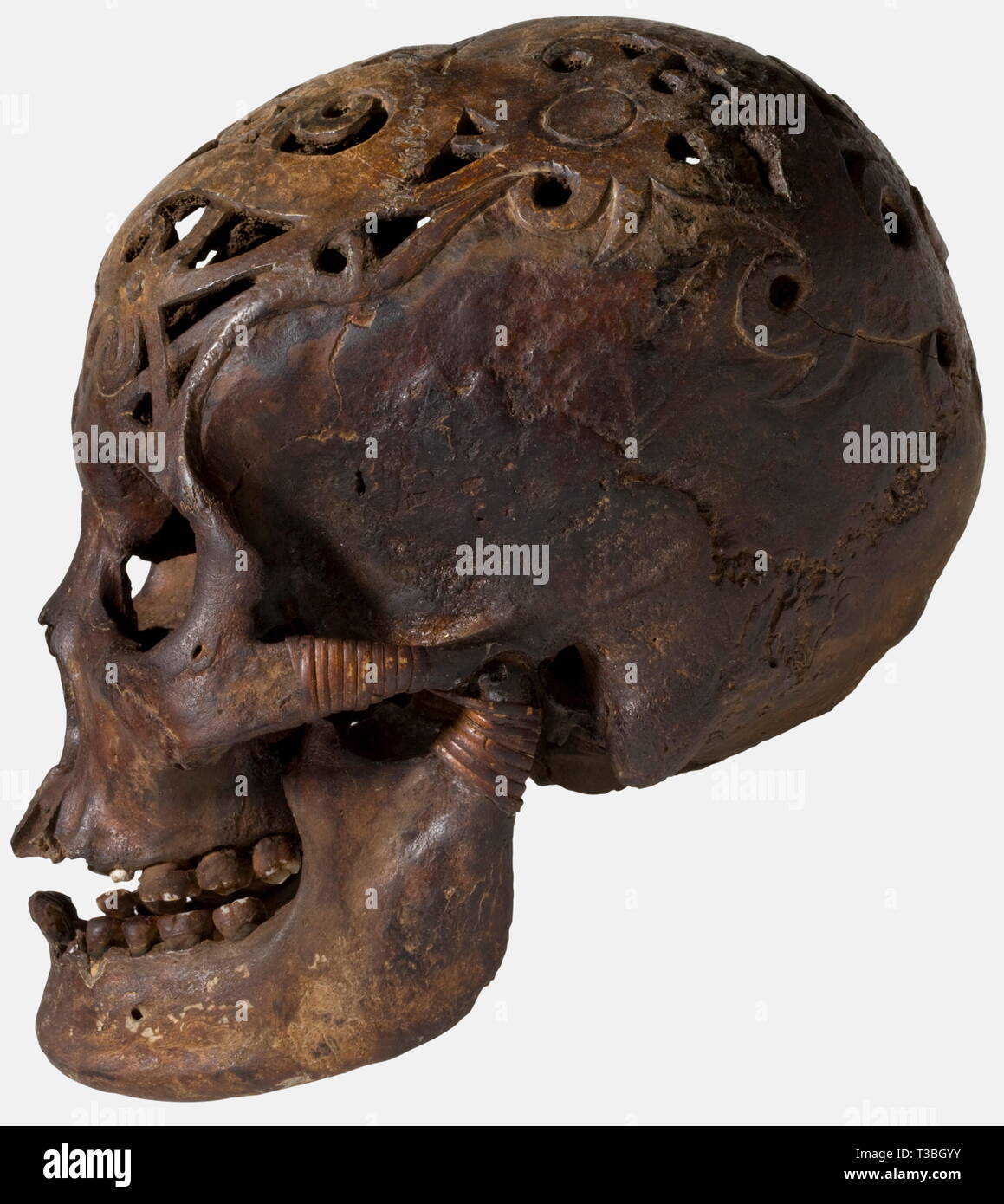 Un teschio trofeo dei DAYAK del BORNEO, riccamente decorate cranio, tutta la calotta superficie interamente scolpito con ornamenti in rilievo forato. Il vasetto inferiore fissato in corrispondenza del giunto per mezzo di una rete di rattan. Tutto il cranio colorati e patinato, alcuni denti sono mancanti, alcune parti con piccole crepe, il barattolo inferiore parzialmente sostituiti e riparati. Altezza 20 cm. Alcune tribù dayak praticata la caccia di testa, cioè la testa del nemico sconfitto era considerata come prova di mascolinità del vincitore e costretto l'anima del perdente per servire il conquistatore nel, Additional-Rights-Clearance-Info-Not-Available Foto Stock