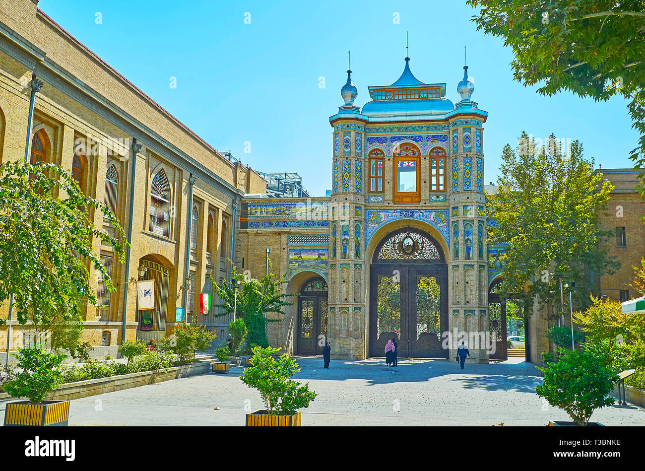 TEHRAN, IRAN - 25 ottobre 2017: a piedi lungo la strada ombreggiata di Bagh-e Melli giardino con una vista sull'ornato Sardar-e Bagh-e Melli gate con traditio Foto Stock