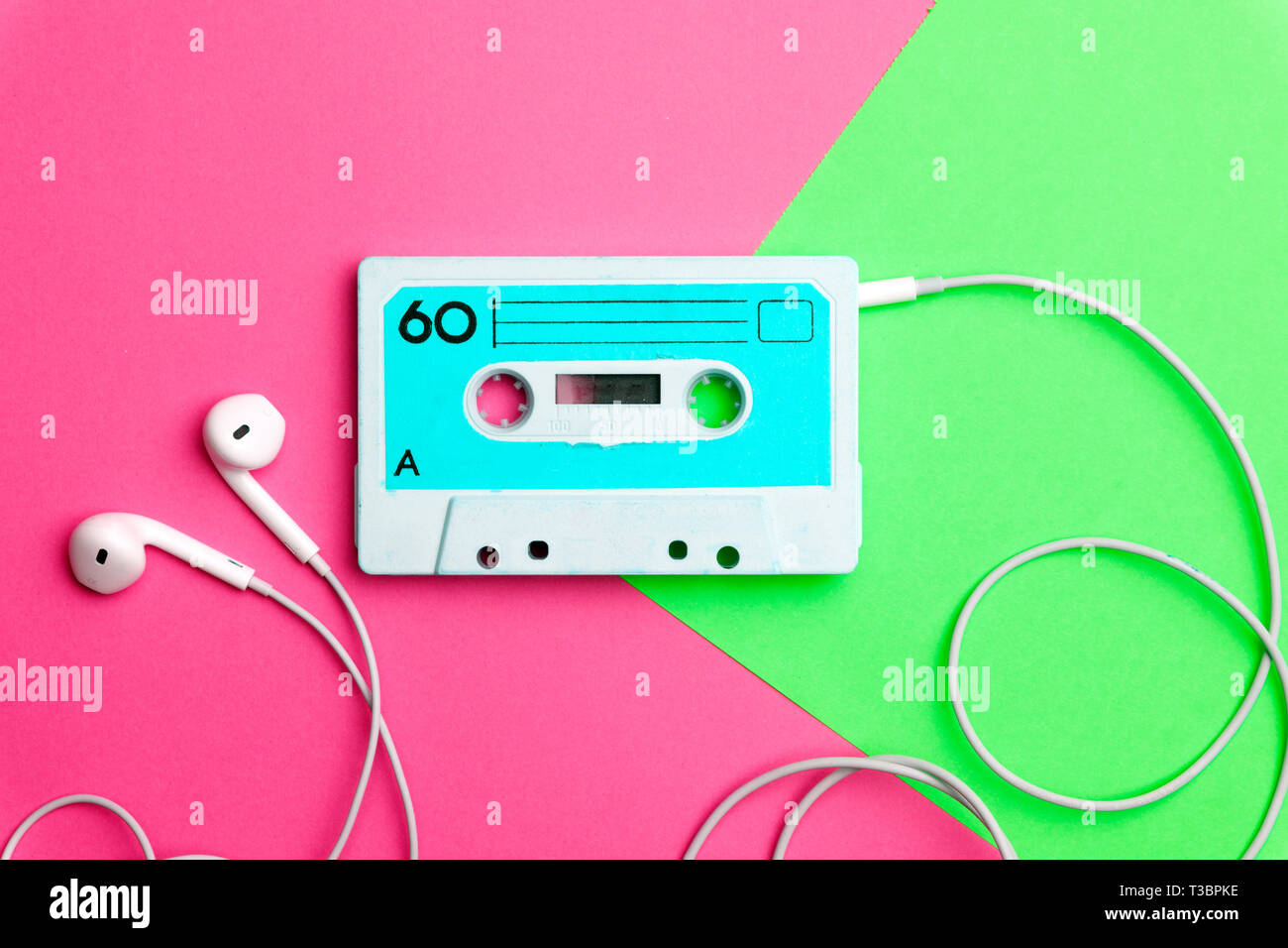 La musica pop gli attributi di stile degli anni ottanta, retro vecchia scuola 80-s o 90-concetto s. Cassetta audio su un luminoso blu-rosa background creativo Foto Stock