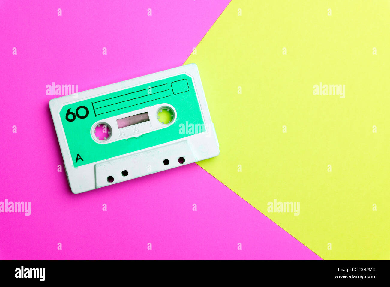 La musica pop gli attributi di stile degli anni ottanta, retro vecchia scuola 80-s o 90-concetto s. Cassetta audio su un luminoso blu-rosa background creativo Foto Stock