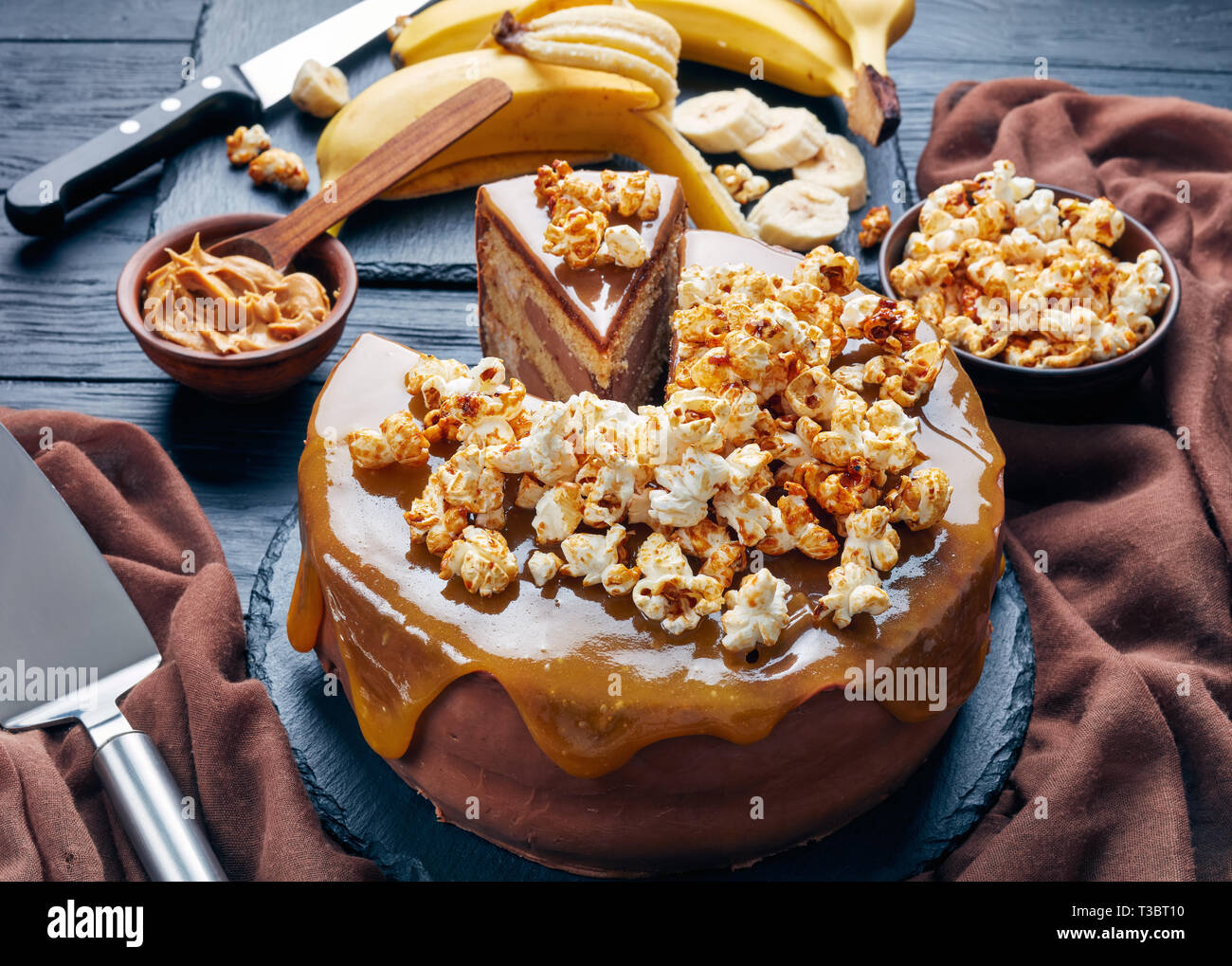 Close-up di una banana a fette di pan di spagna a strati con burro di arachidi mousse e guarnita con glassa al cioccolato fuso caramello e popcorn dolce, Horizon Foto Stock