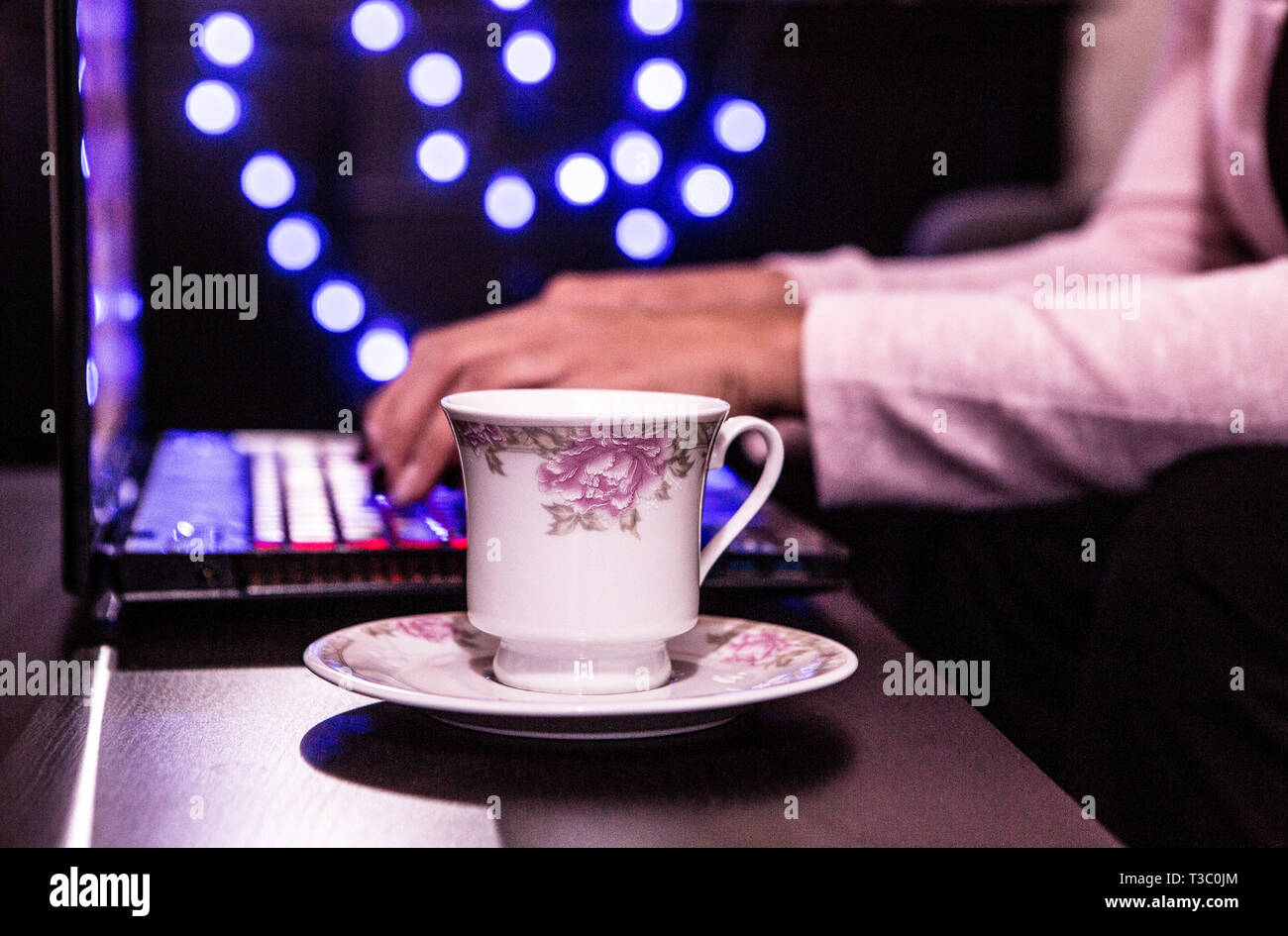 Vista laterale di una donna digitando su un laptop con caffè in un retrò Ambiente di lavoro Foto Stock