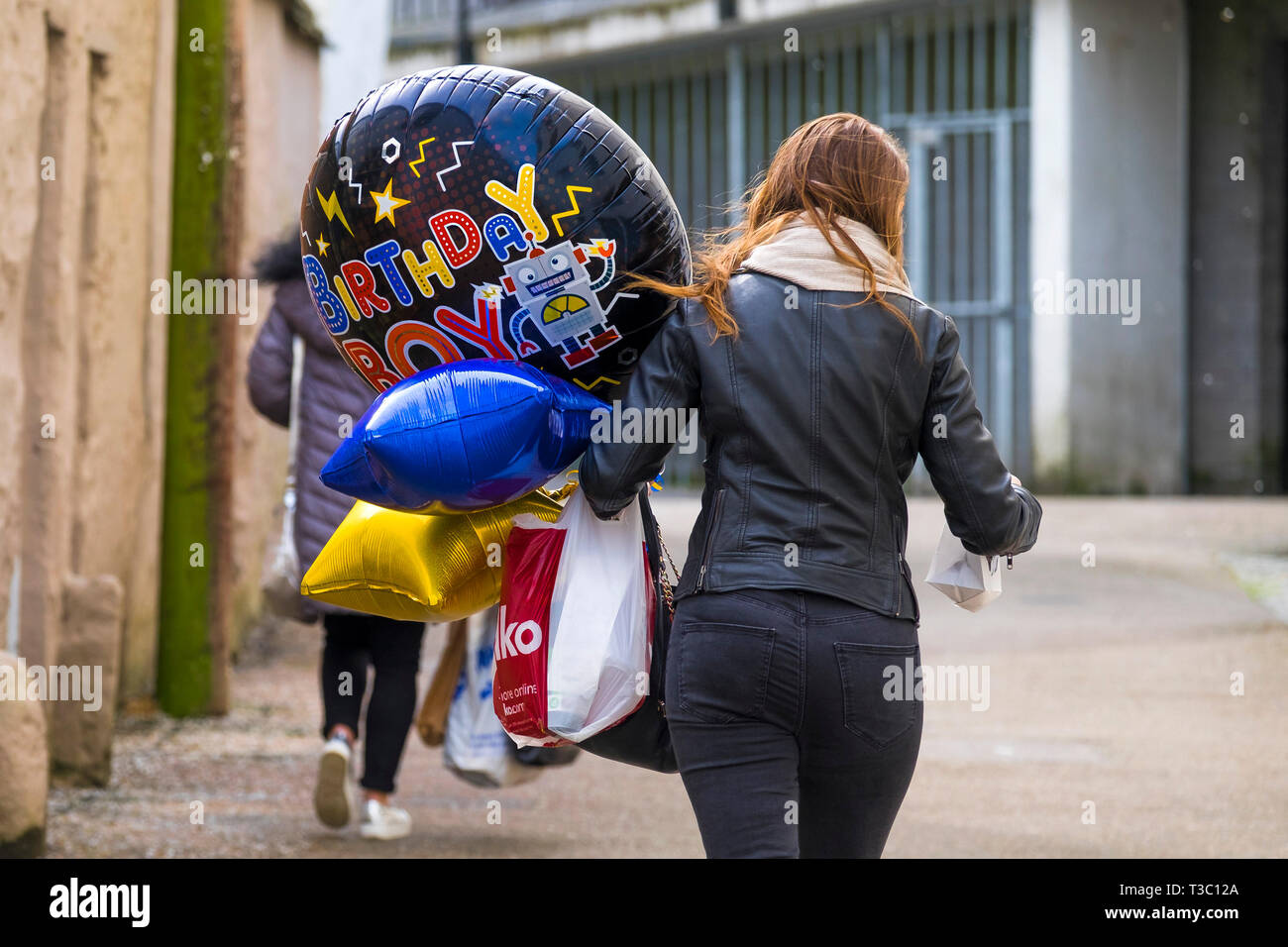 Una donna che cammina e portante colorati palloncini di compleanno. Foto Stock