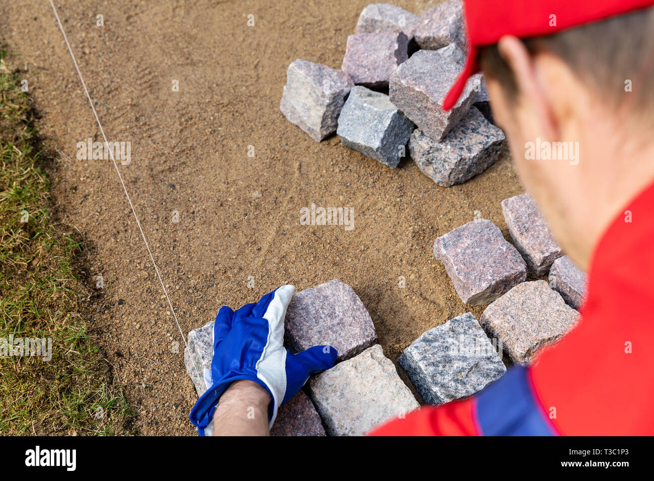 Costruzione di pavimentazione - lavoratore la posa di pietra in granito lastricatori Foto Stock