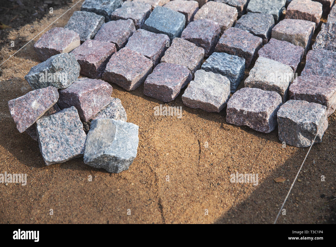 Pavimentazione in ciottoli - pietra di granito lastricatori sulla ghiaia Foto Stock