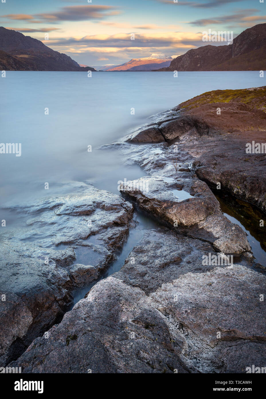 La vista sul Loch Maree dalla costa rocciosa del lontano sole di setting, Wester Ross, Scozia Foto Stock