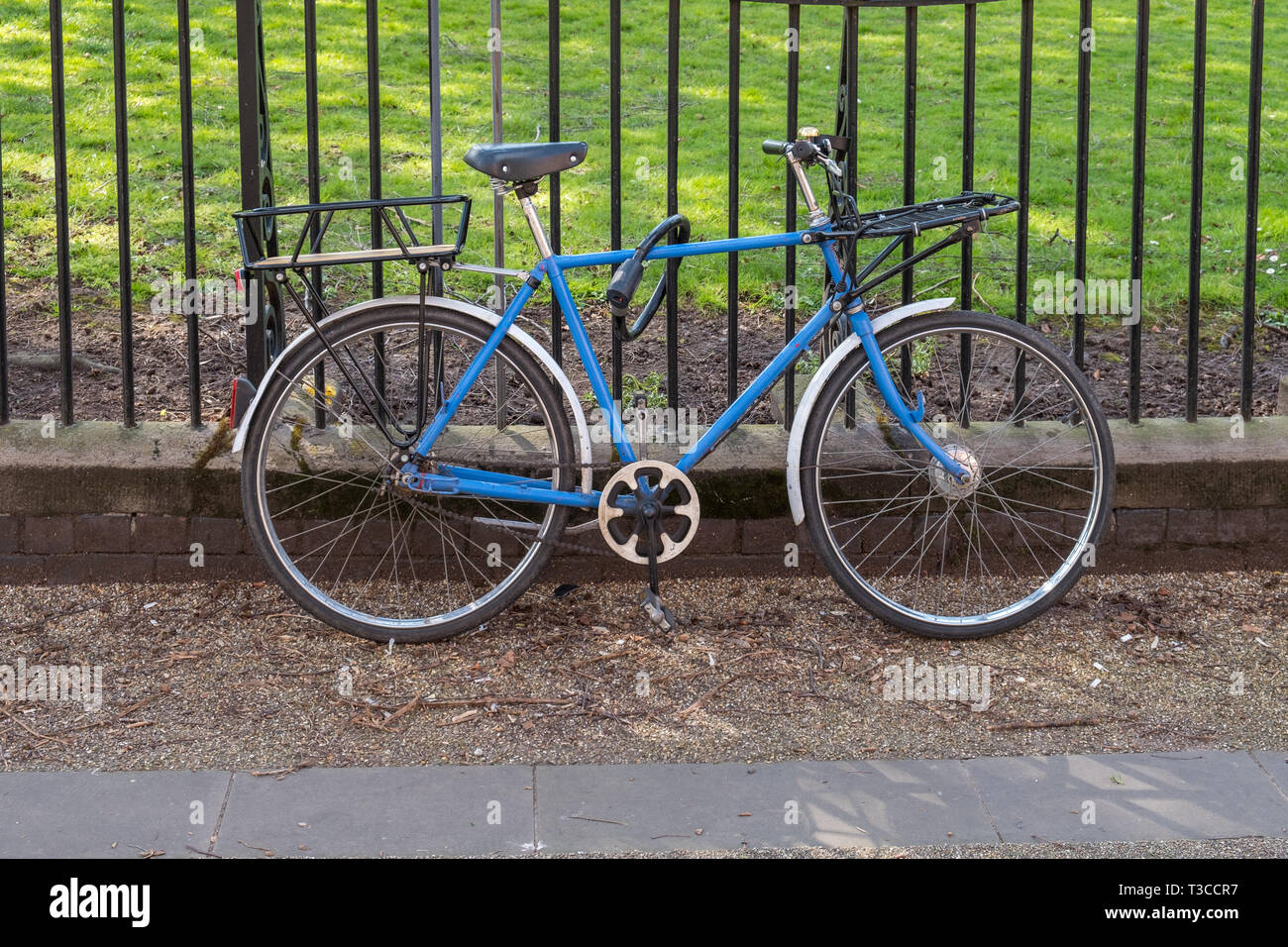 Vecchio Blu bicicletta appoggiata contro le ringhiere in New Walk, Leicester, Regno Unito Foto Stock