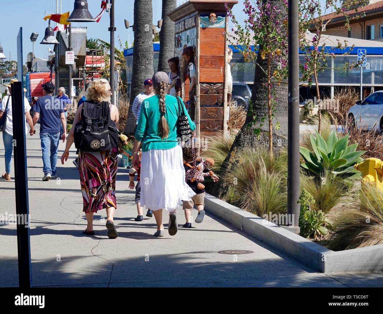 Due donne a piedi con i bimbi a indossare i cavi elettrici e guinzagli, Ventura Harbor, Ventura, California, Stati Uniti d'America. Foto Stock