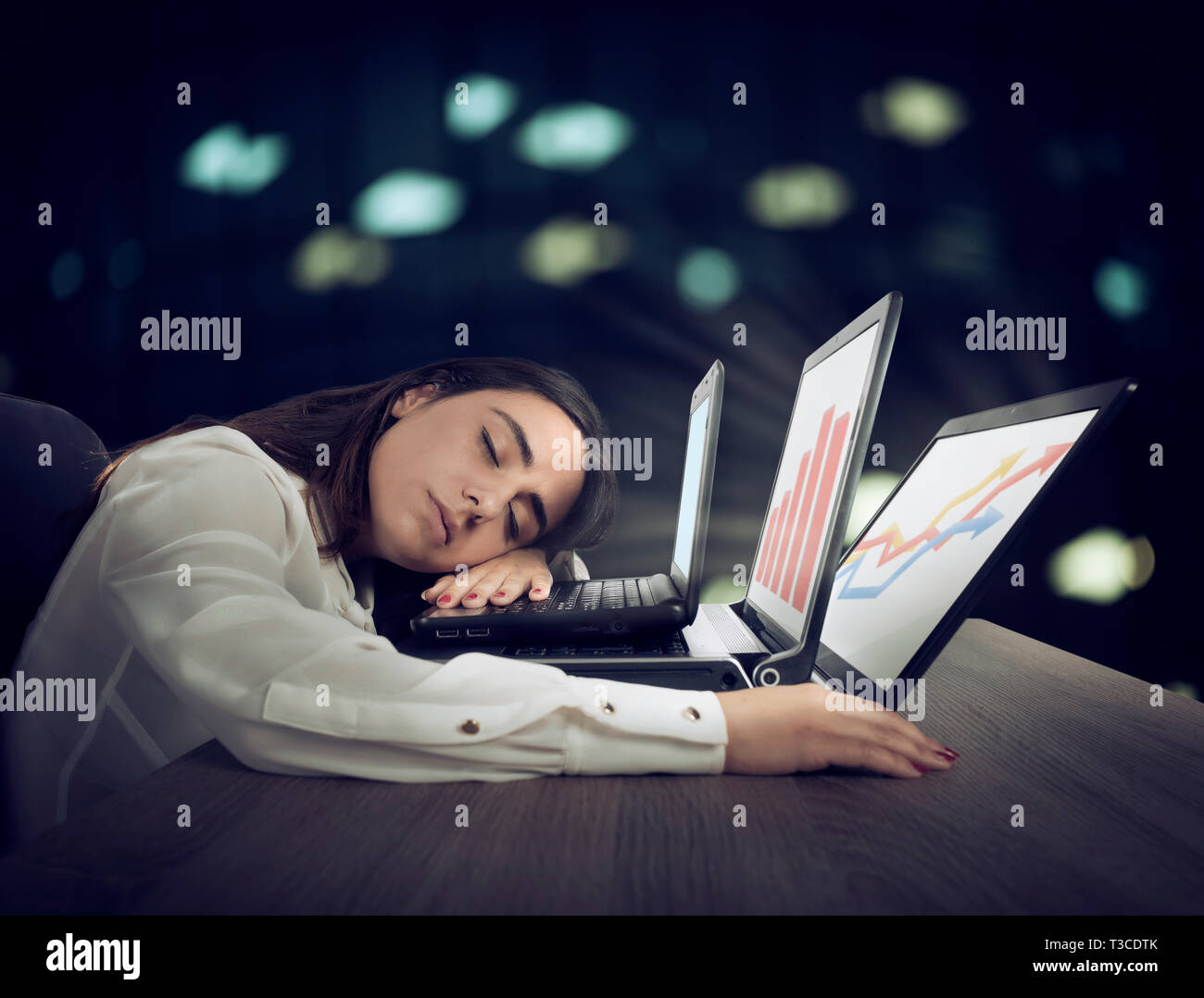Lavoratore di sesso femminile che si addormenta lavorando simultaneamente su tre laptop Foto Stock