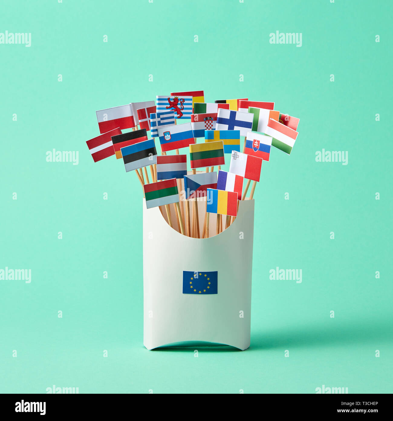 Set di diverse bandiere di carta in una scatola di cartone decorata con segno dell'UE su sfondo verde con copia spazio. Economico, politico Unione di Stati europei Foto Stock