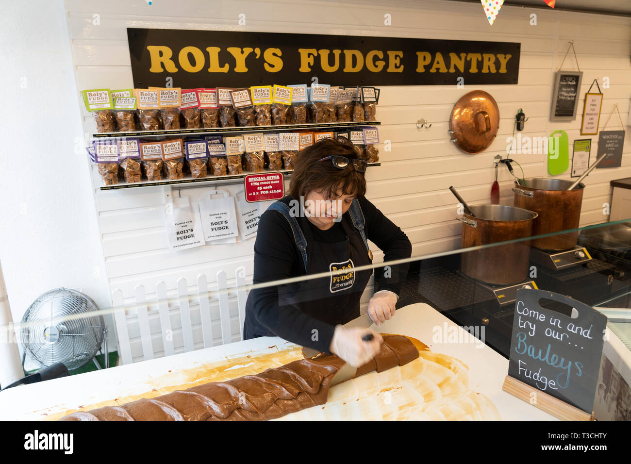 Una farsa maker in Roly's Fudge Pantry in Stratford upon Avon rendendo fudge nel metodo tradizionale mediante agitazione la salsa con un dispositivo di compressione Foto Stock