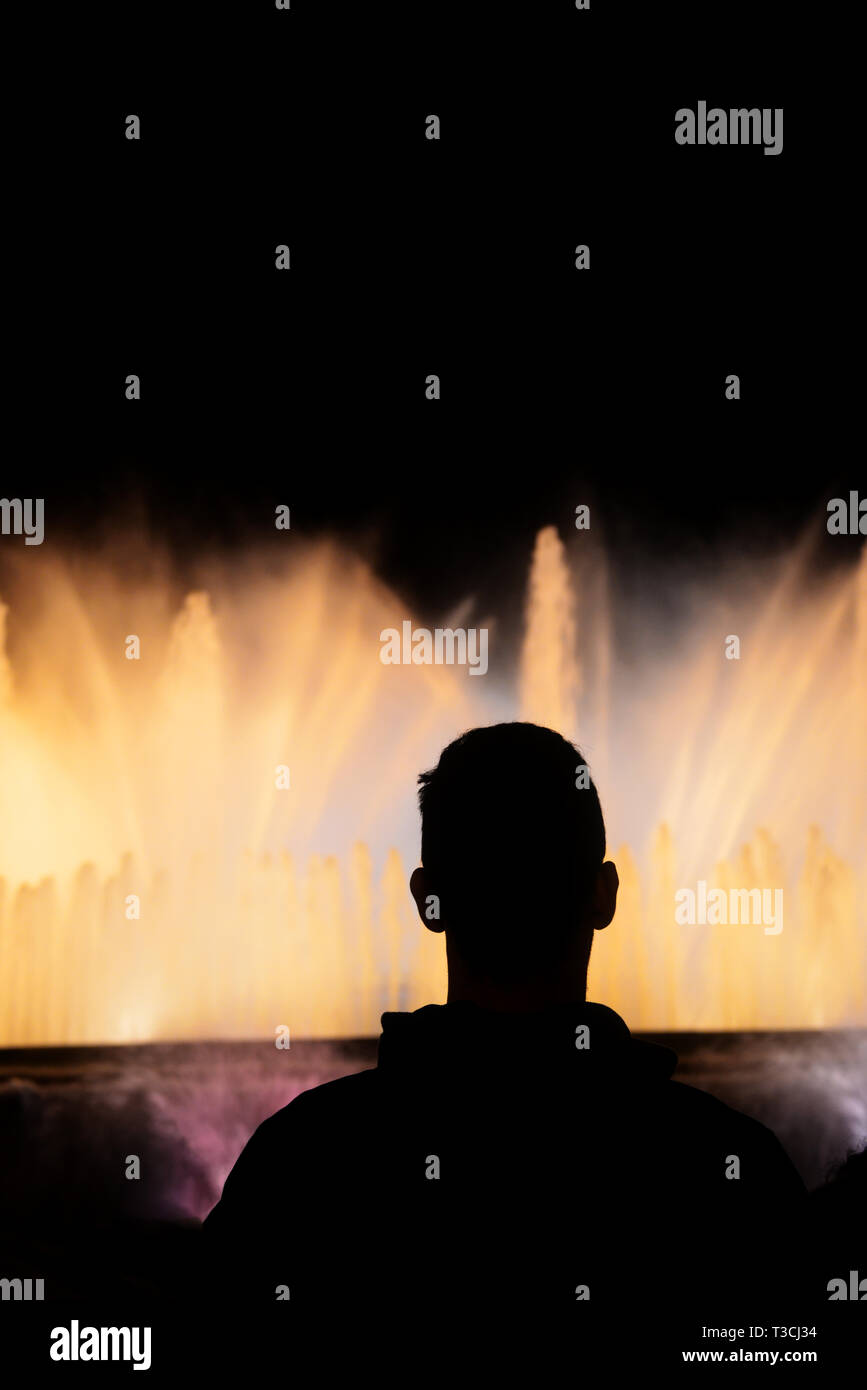 Silhouette di un giovane uomo guarda la fontana di notte Foto Stock