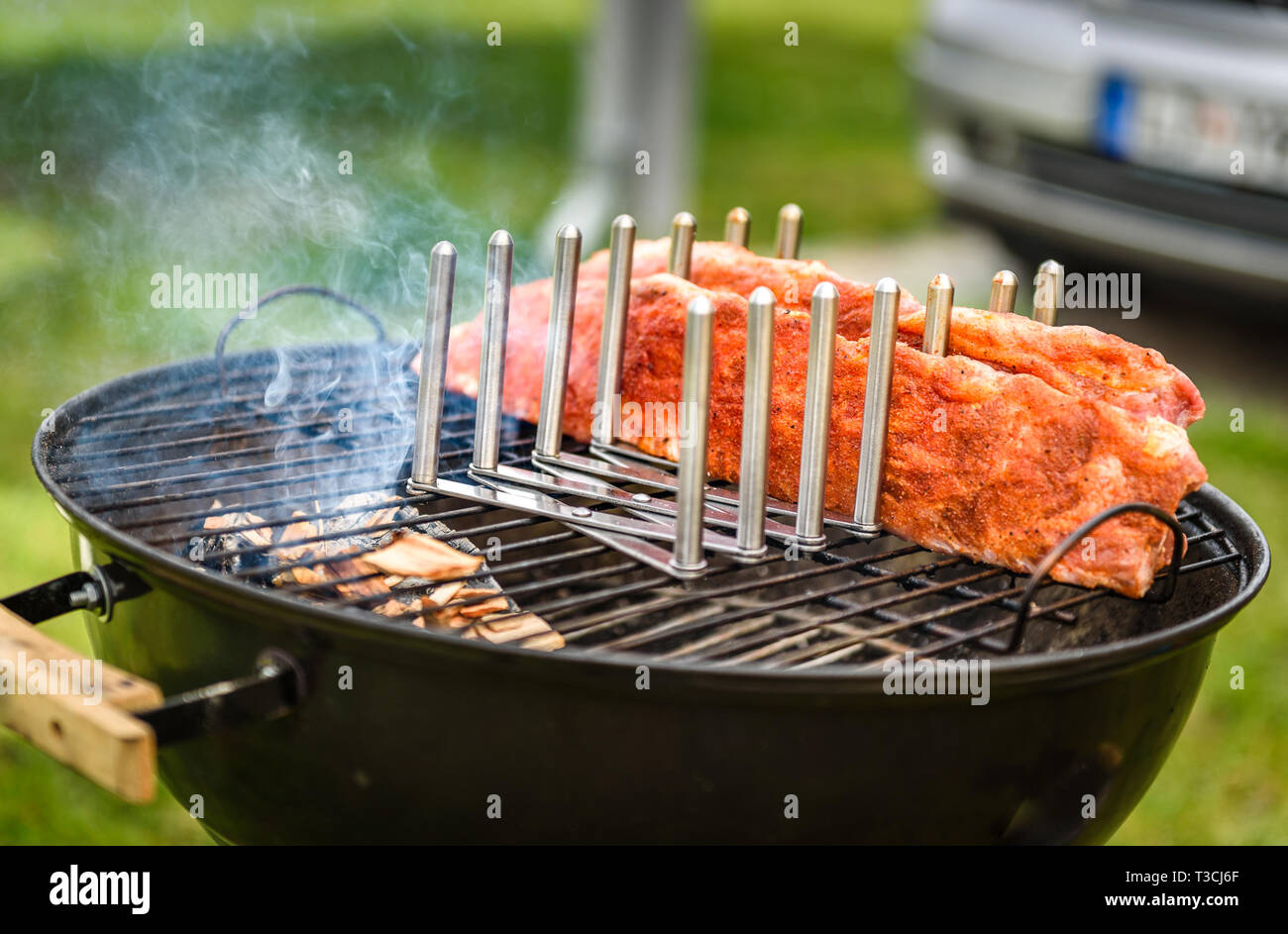 Bimbo indietro costine arrosto su barbecue bollitore barbecue grill. Home reso costolette di maiale alla griglia con una marcia bassa e molto lentamente. La cottura alla griglia all'aperto in natura a fami Foto Stock