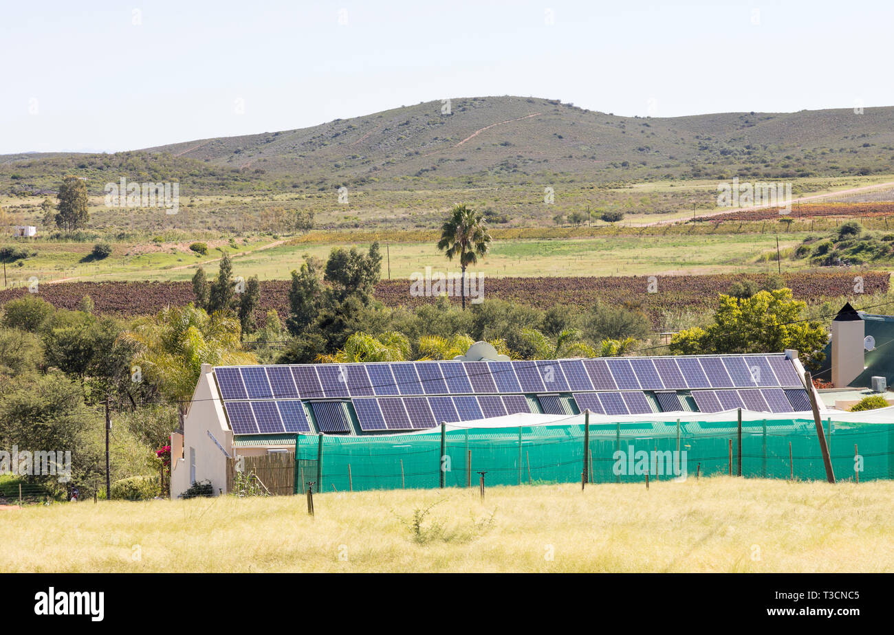 Rispettosi dell'ambiente casa colonica con tetto a pannelli solari fotovoltaici fornendo fonti di energia e di elettricità in un paesaggio rurale, Sud Afri Foto Stock