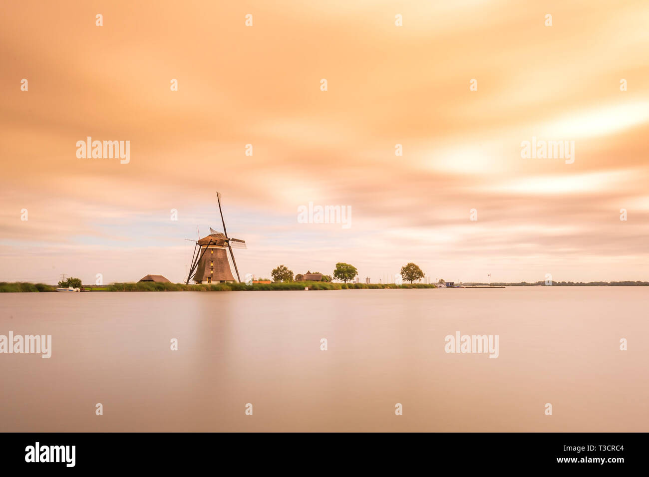 Il paesaggio durante un bel colore arancione tramonto con cielo velato e un vecchio Olandese tradizionale mulino a vento si trova a Rottemeren lago vicino a Rotterdam. Foto Stock