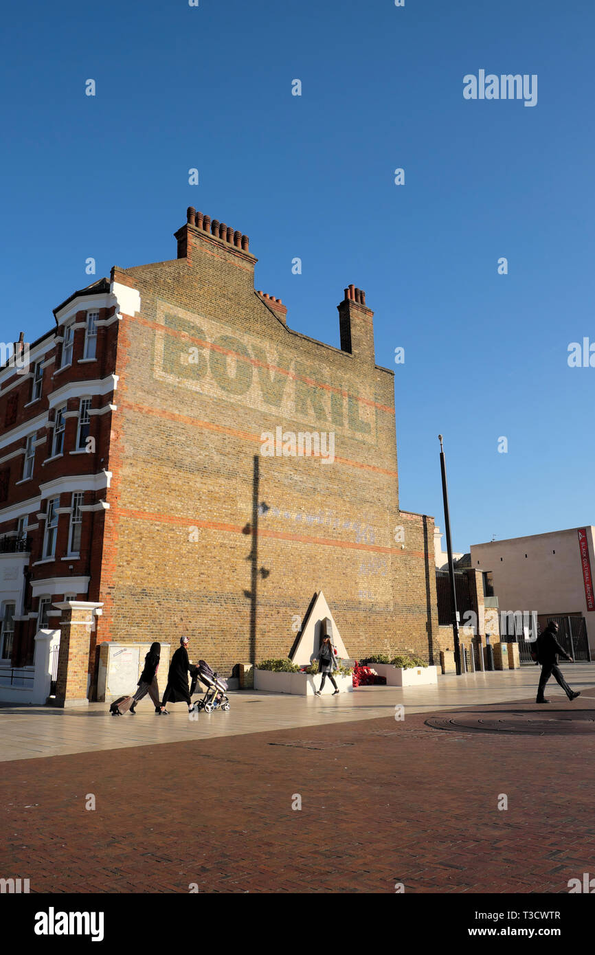 Vista verticale della gente camminare pedoni in Windrush Square e il Bovril edificio con cielo blu in Brixton a sud di Londra Inghilterra REGNO UNITO KATHY DEWITT Foto Stock