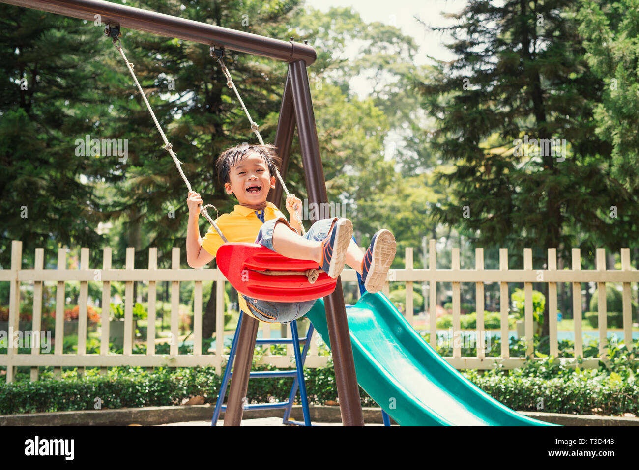 Ragazzo di gioiosa nella scuola elementare età cavallo giocattolo sul parco giochi per bambini Foto Stock