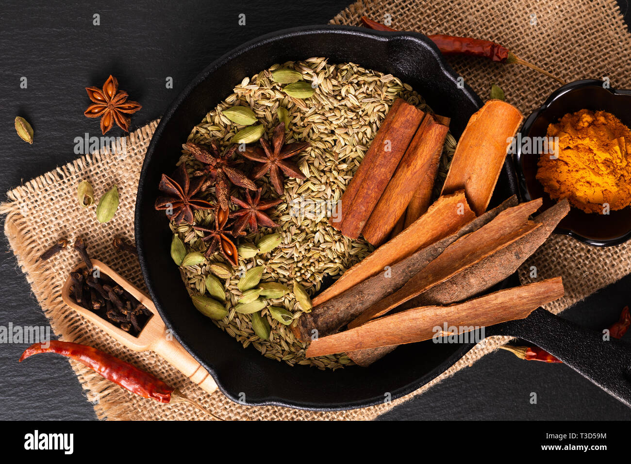 A base di erbe esotiche Food concept Mix di spezie organico la stecca di cannella e i semi di cardamomo e i chiodi di garofano, anice stellato e semi di finocchio in slilet colato su una spranga di nero Foto Stock