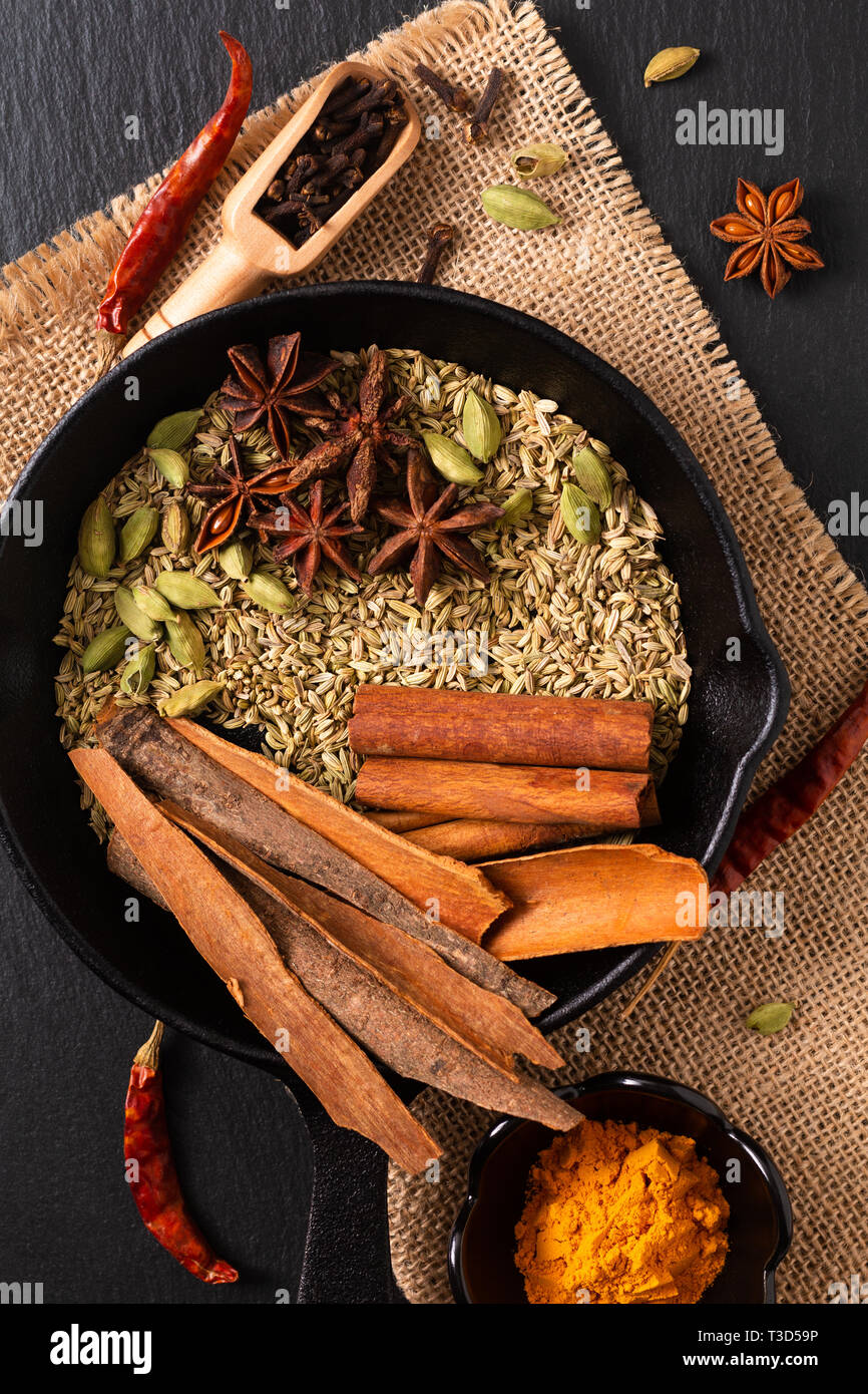 A base di erbe esotiche Food concept Mix di spezie organico la stecca di cannella e i semi di cardamomo e i chiodi di garofano, anice stellato e semi di finocchio in slilet colato su una spranga di nero Foto Stock