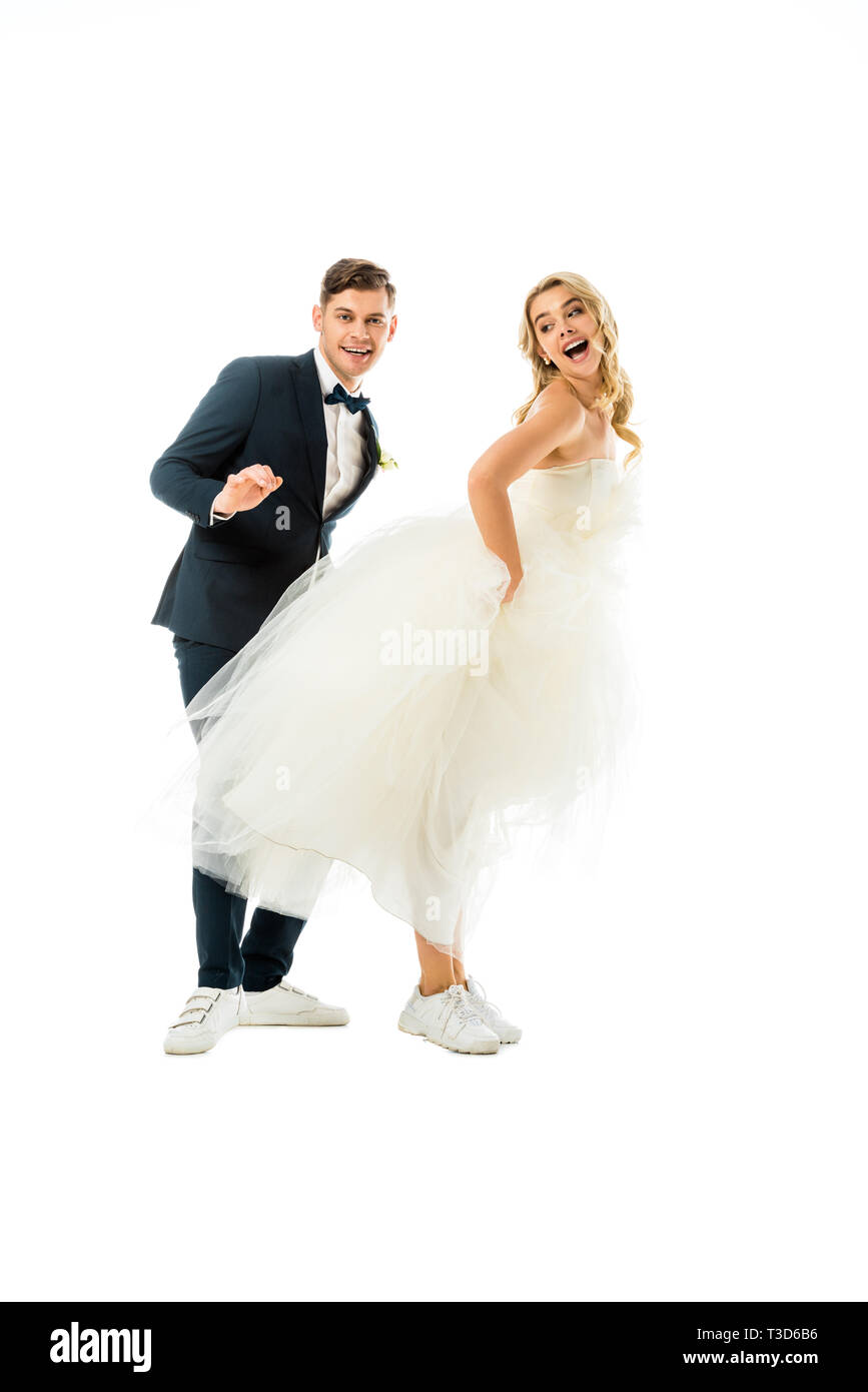 Allegro per lo sposo e la sposa dancing in eleganti vestiti e scarpe da  ginnastica isolato su bianco Foto stock - Alamy